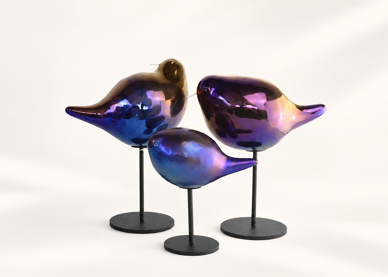 Three iridescent ceramic birds on stands