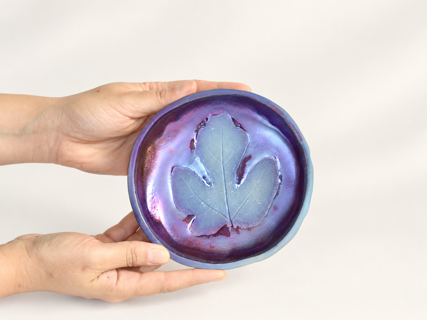 Iridescent ceramic dish with leaf impression
