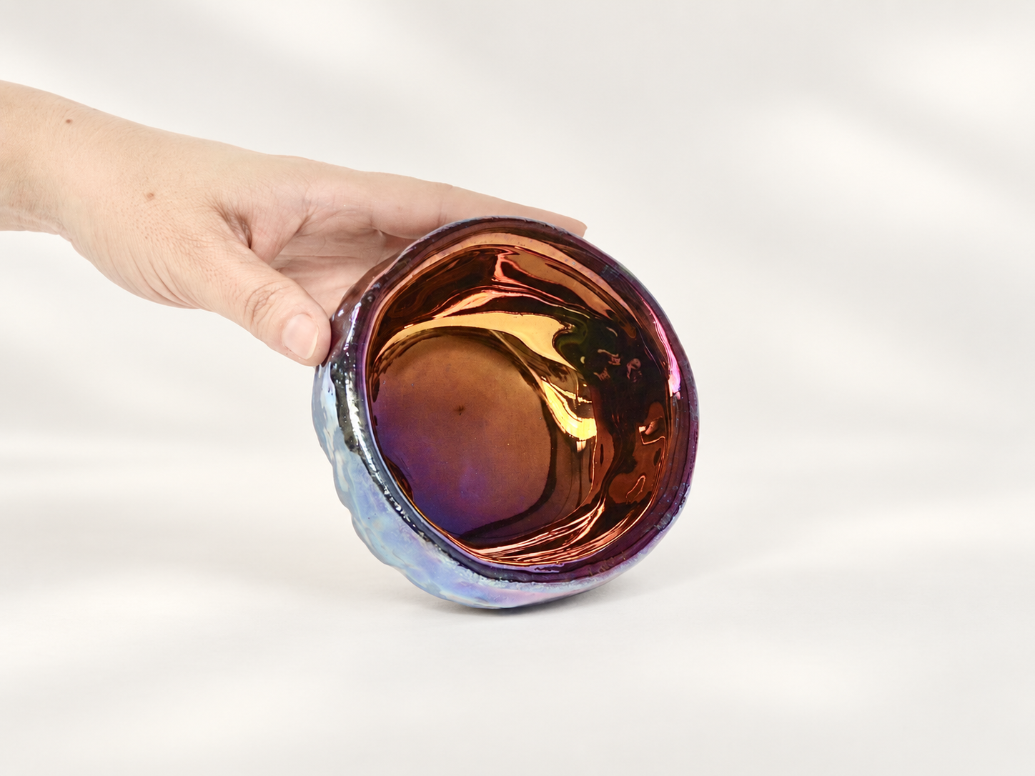 Copper lustre ceramic bowl held by hand