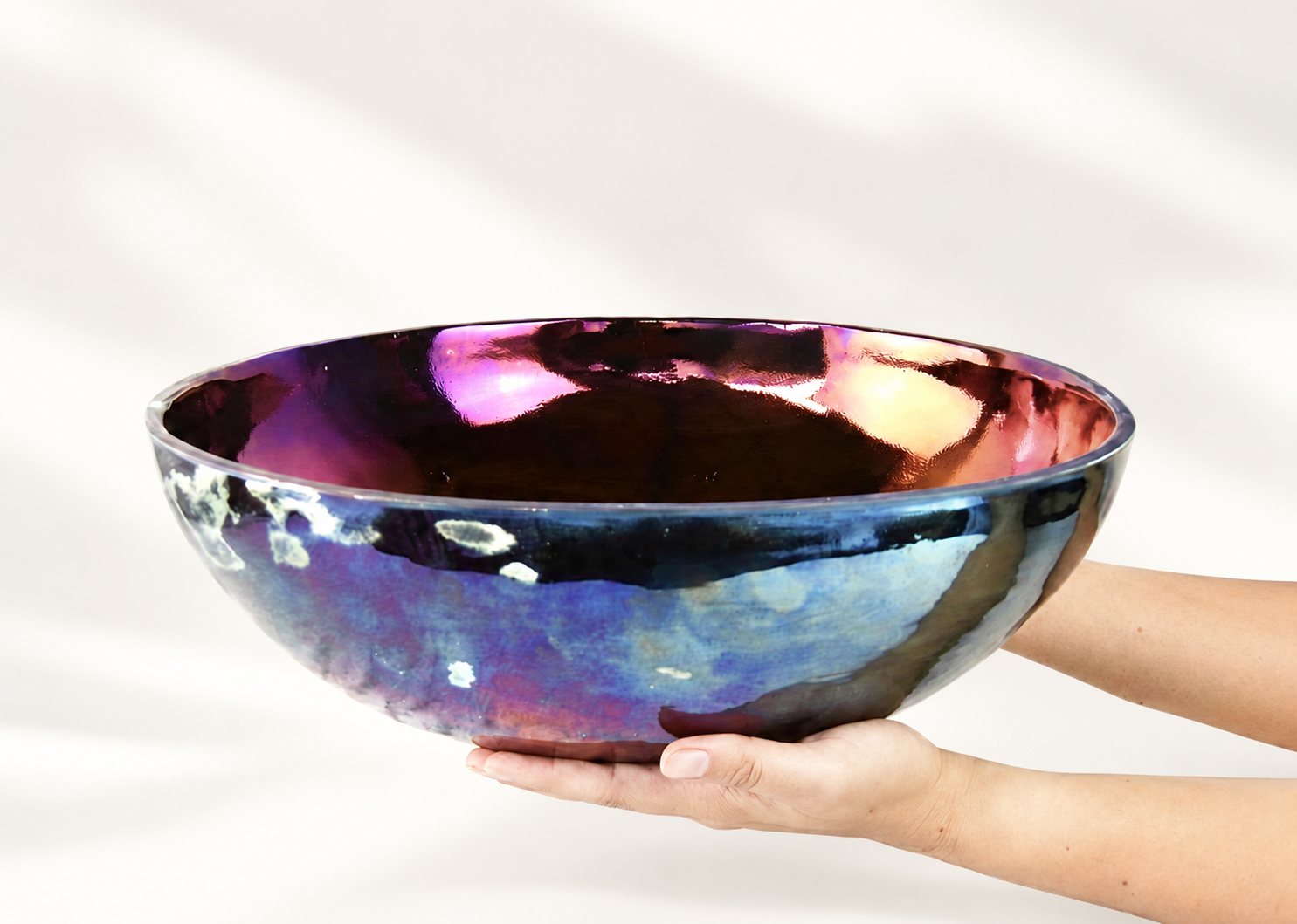 Large iridescent ceramic bowl held by hand